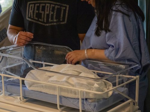 Parents watching a sleeping baby.