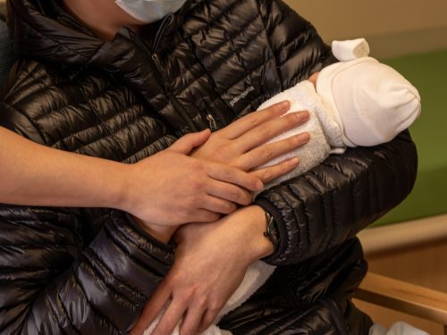 Two people embracing a baby.